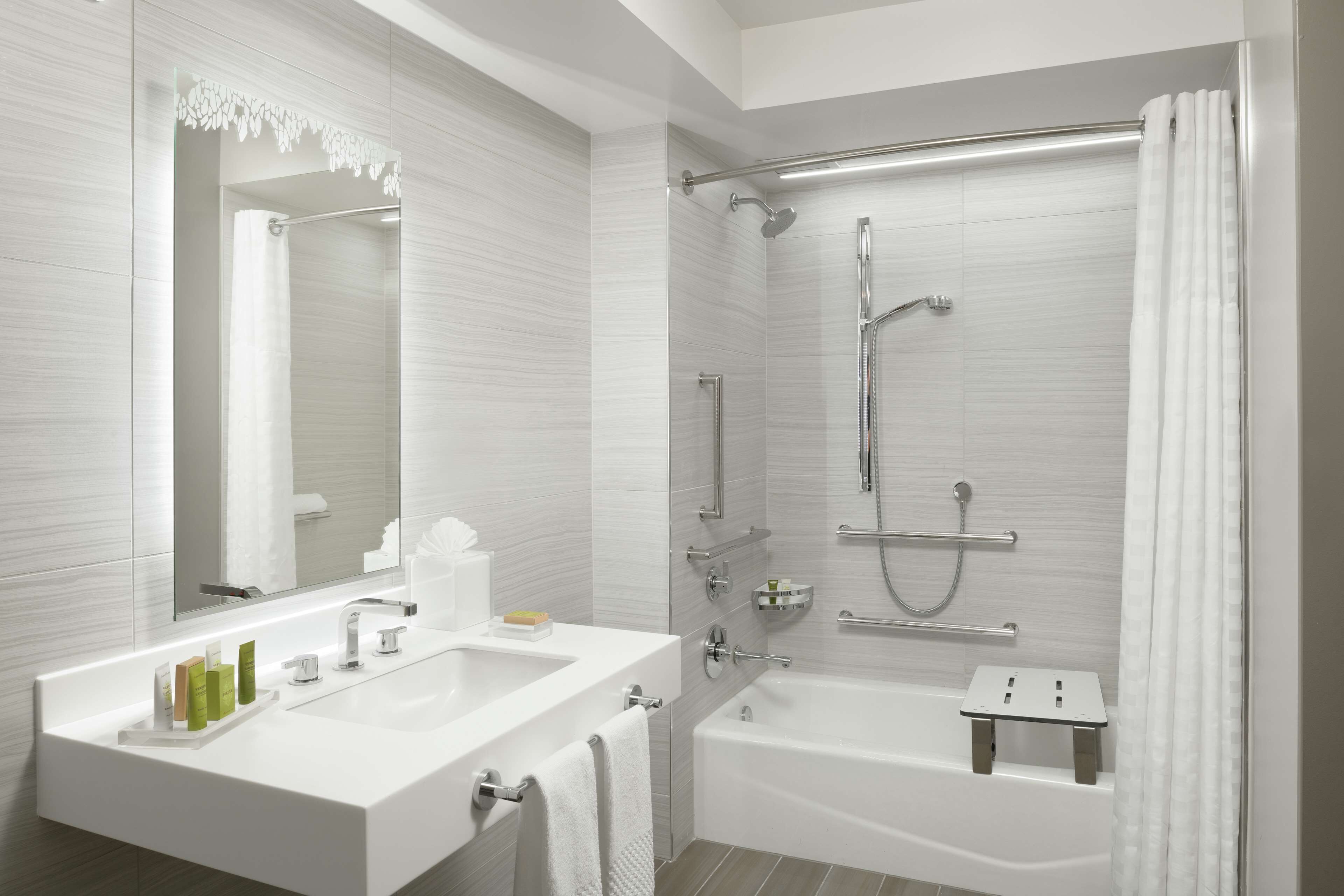 Un baño moderno con tocador doble, bañera, ducha con puerta de cristal y un espejo grande.
