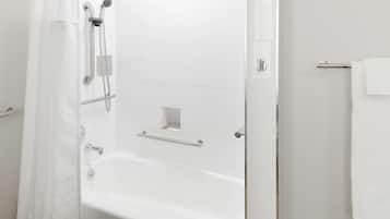 A modern bathroom with a white bathtub, a shower with a glass door, and a towel rack.