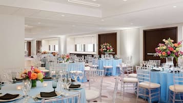 Una sala de banquets amb taules rodones, cadirees transparents i estovalls blaus.