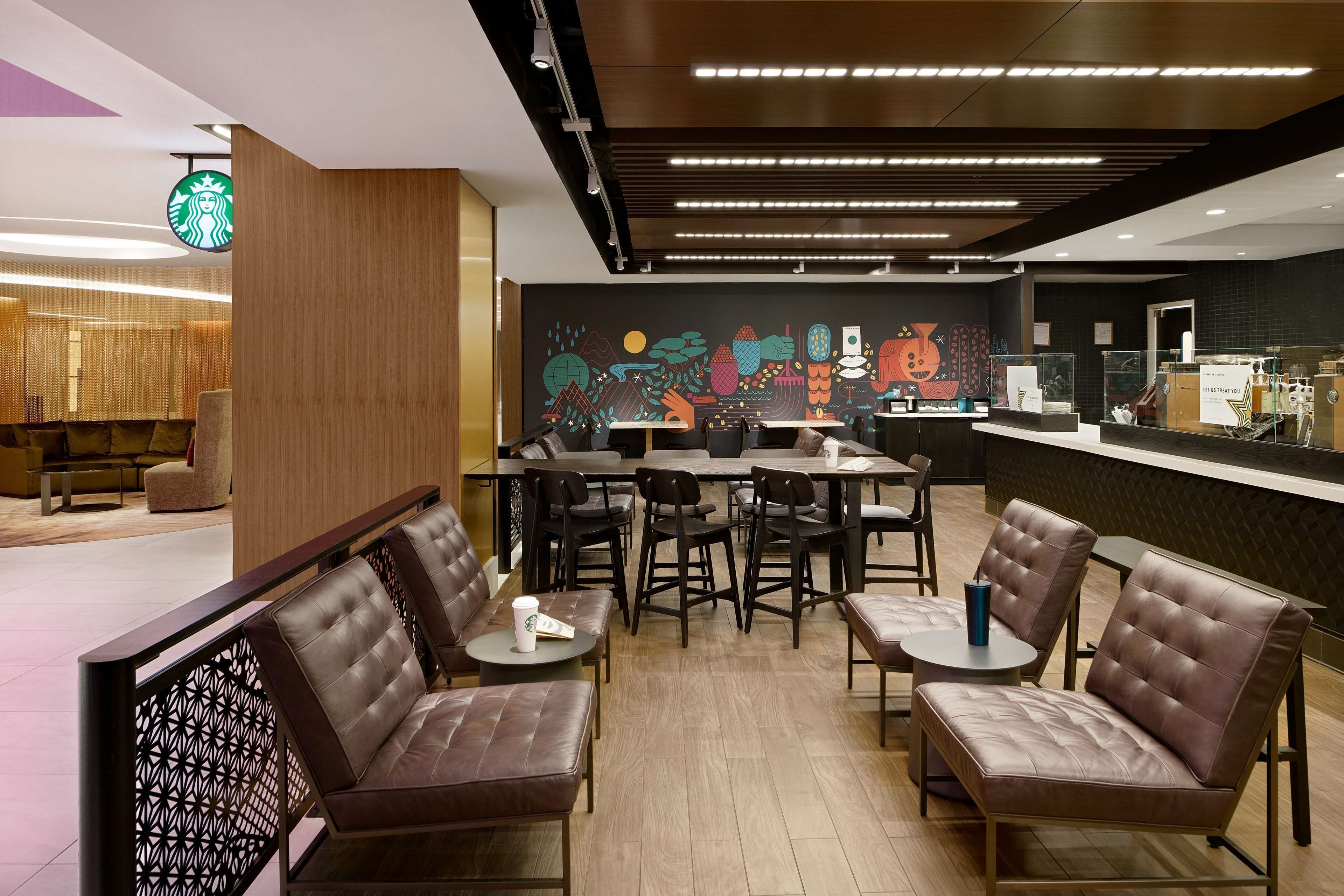 A modern Starbucks with leather seating, wooden accents, and a colorful mural.