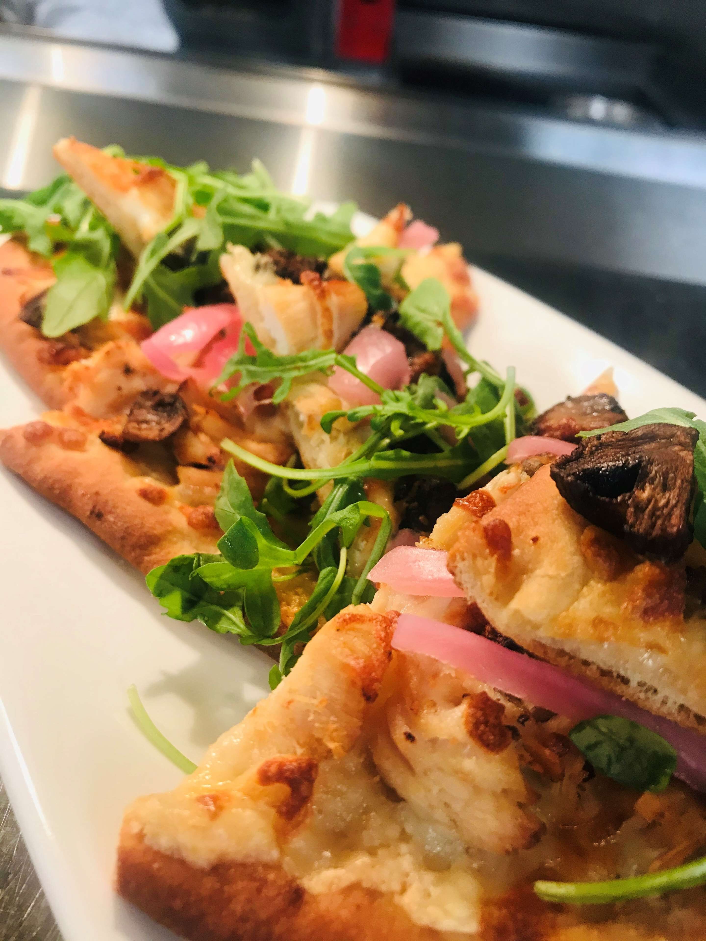 Un piatto di pizza condita con verdure e cipolle.