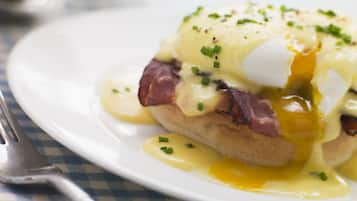 A plate of food with eggs, ham, and sauce.