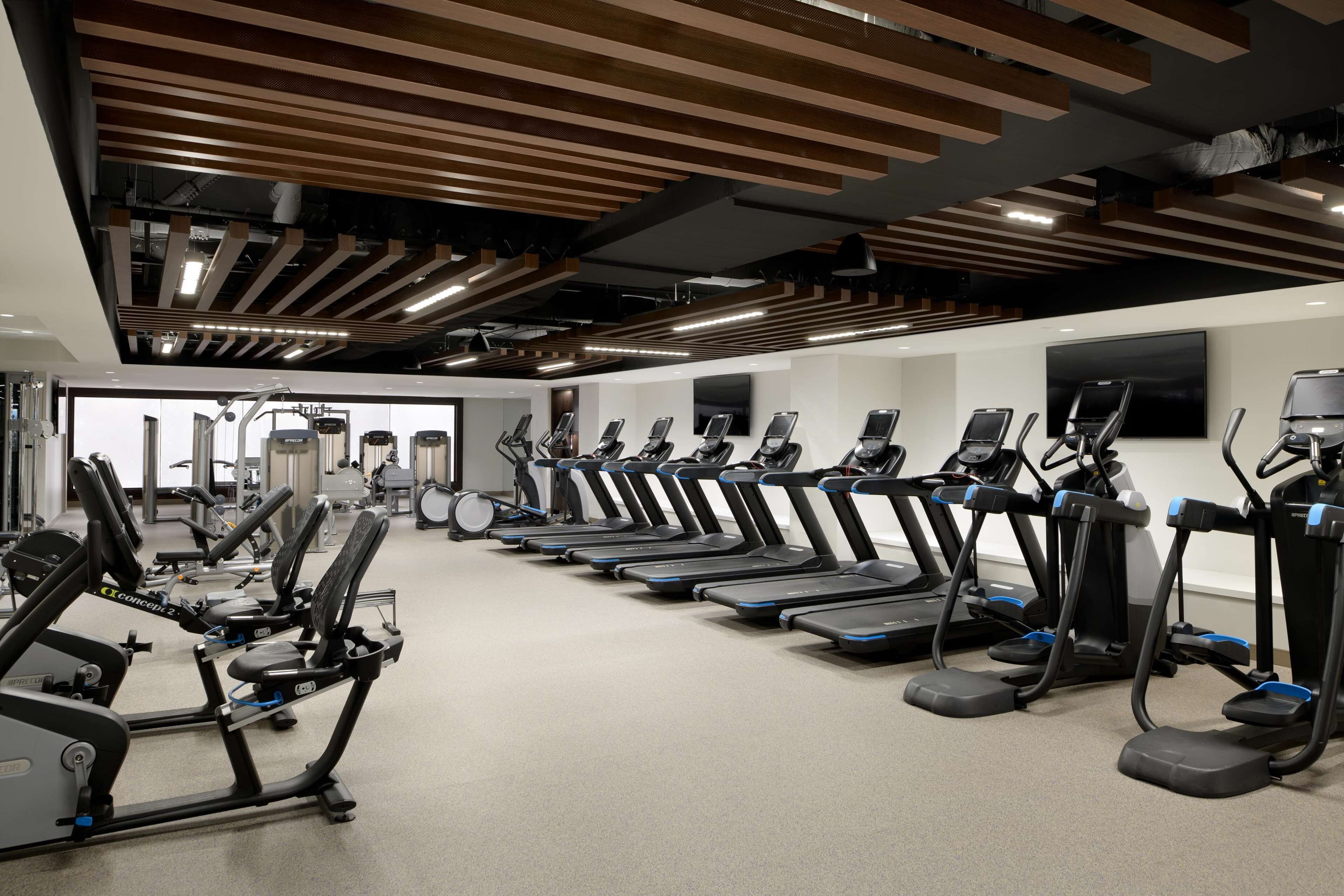 Un gimnasio con cintas de correr y equipo de ejercicio.