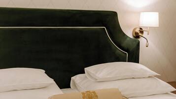 A neatly made bed with white linens and a green upholstered headboard.