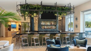 A modern bar area with a curved counter, seating with blue chairs, and a large window offering a view of the outdoors.