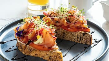 A slice of toast topped with salmon, vegetables, and sprouts on a plate.