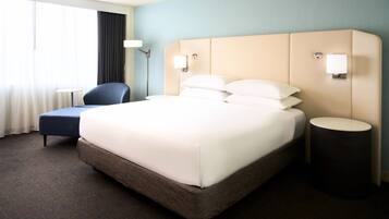 Una habitación de hotel con una cama grande, una silla, una mesita de noche y una lámpara.