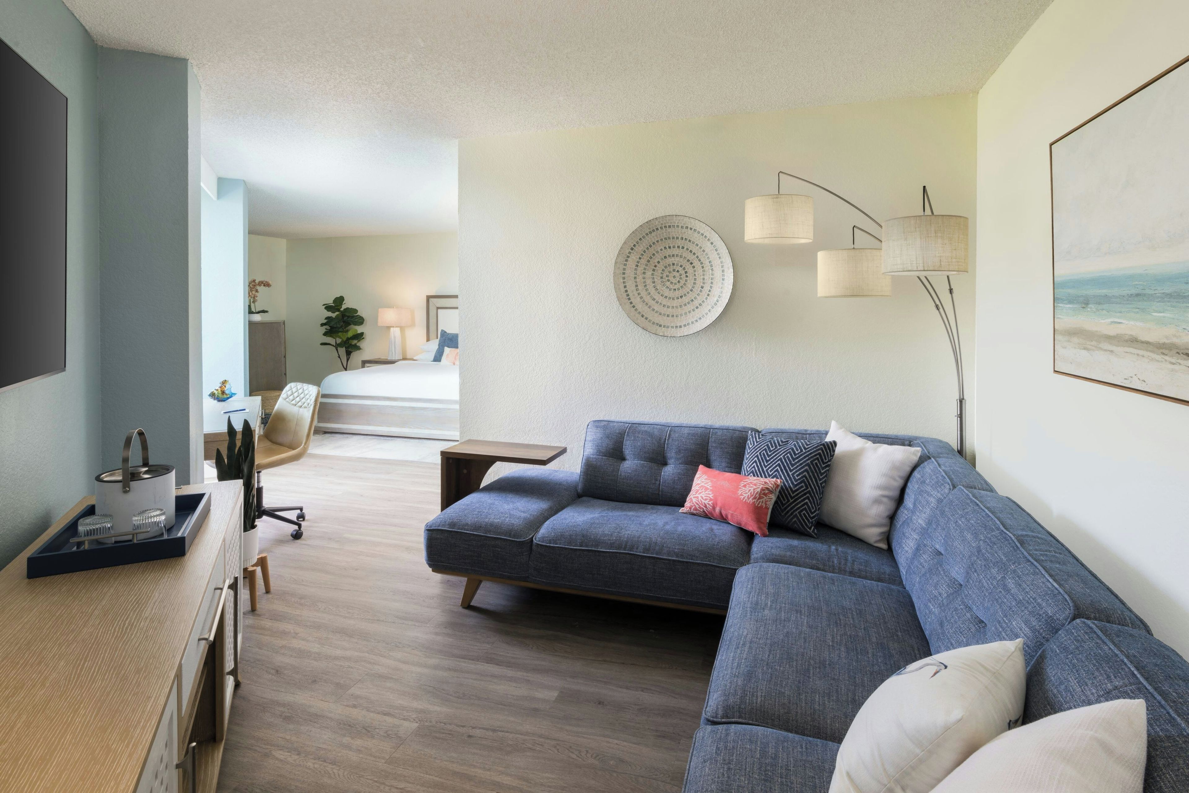 Un salon moderne avec un canapé d’angle, un téléviseur à écran plat et un coin repas comprenant une table et des chaises en bois.