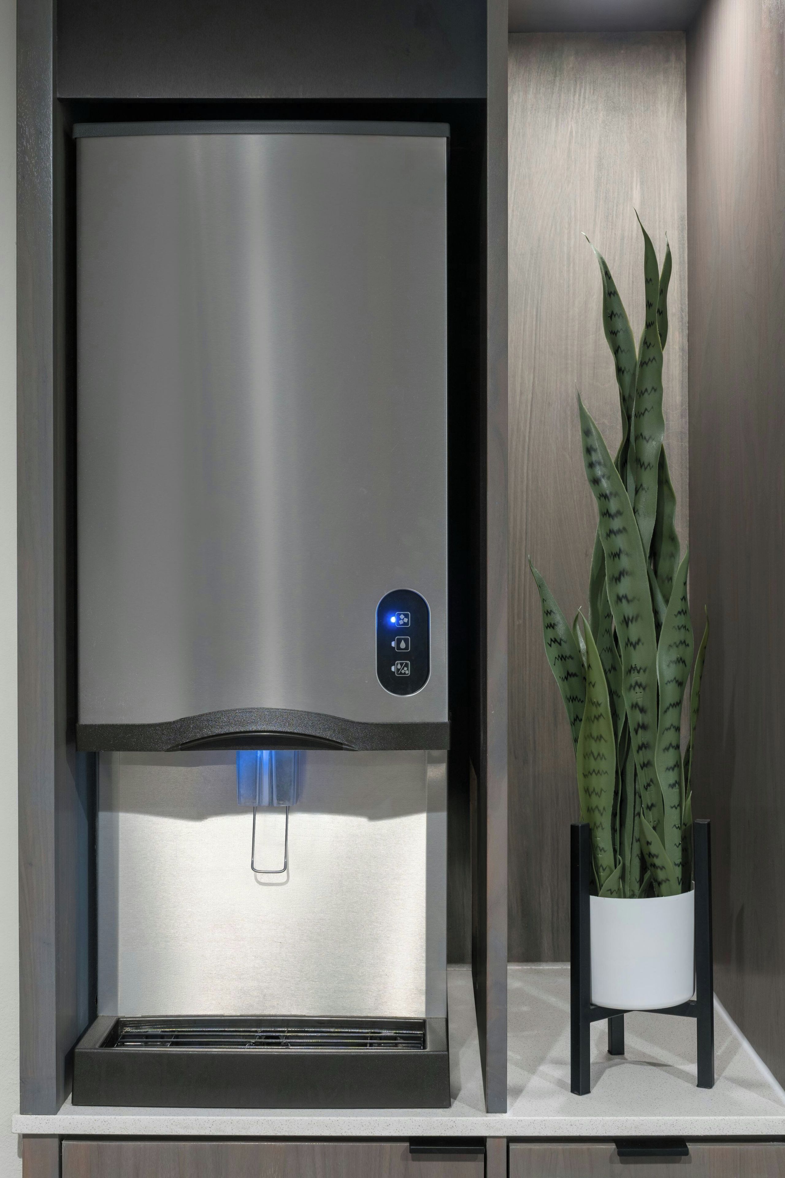 Una cocina moderna con dispensador de agua de acero inoxidable y una planta en maceta.