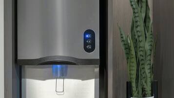 Una cocina moderna con dispensador de agua de acero inoxidable y una planta en maceta.