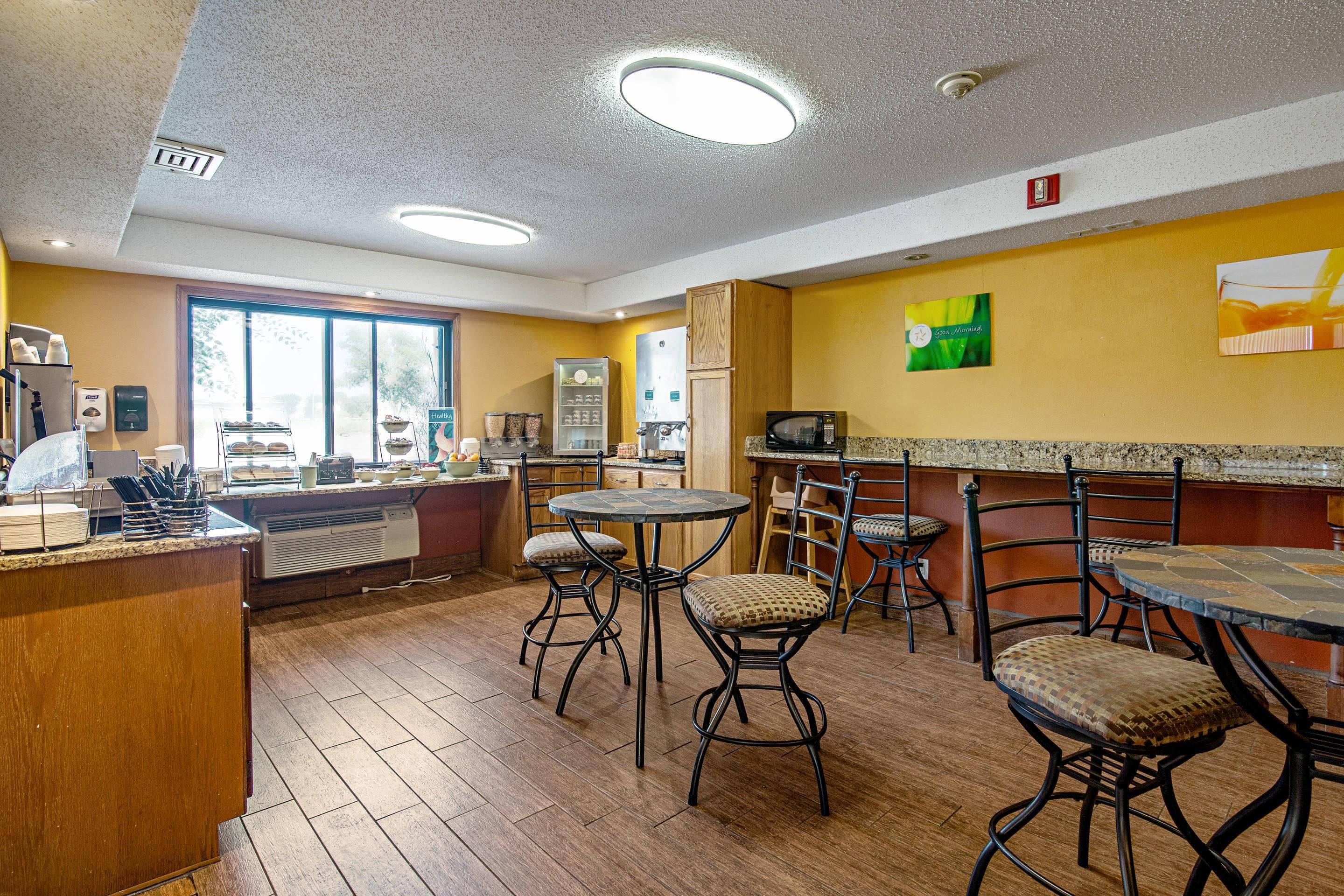 A restaurant with a bar area, seating, and a view of the outdoors.