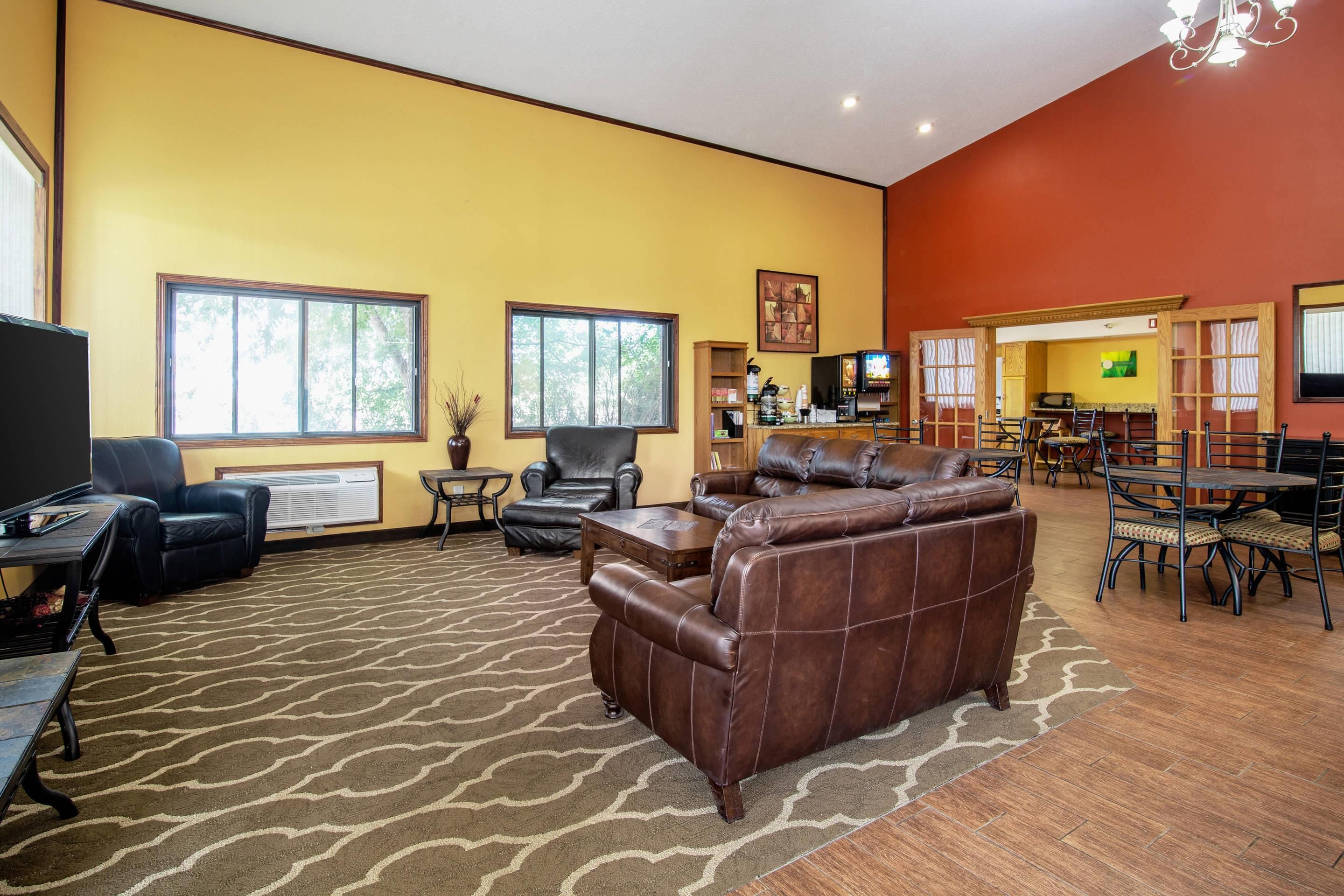 A spacious living room with leather sofas, a dining area, and a kitchen in the background.