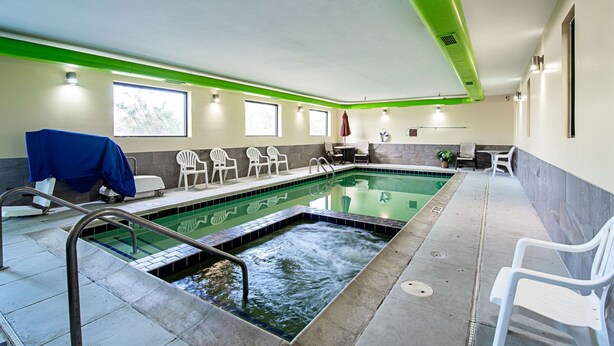 A swimming pool with a water feature, surrounded by white chairs and a sunshade. - Quality Inn Aberdeen (Aberdeen)
