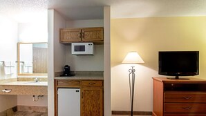 A compact hotel bathroom with a sink, a microwave, a small refrigerator, wooden cabinets, a television, and a floor lamp. - Quality Inn Aberdeen (Aberdeen)