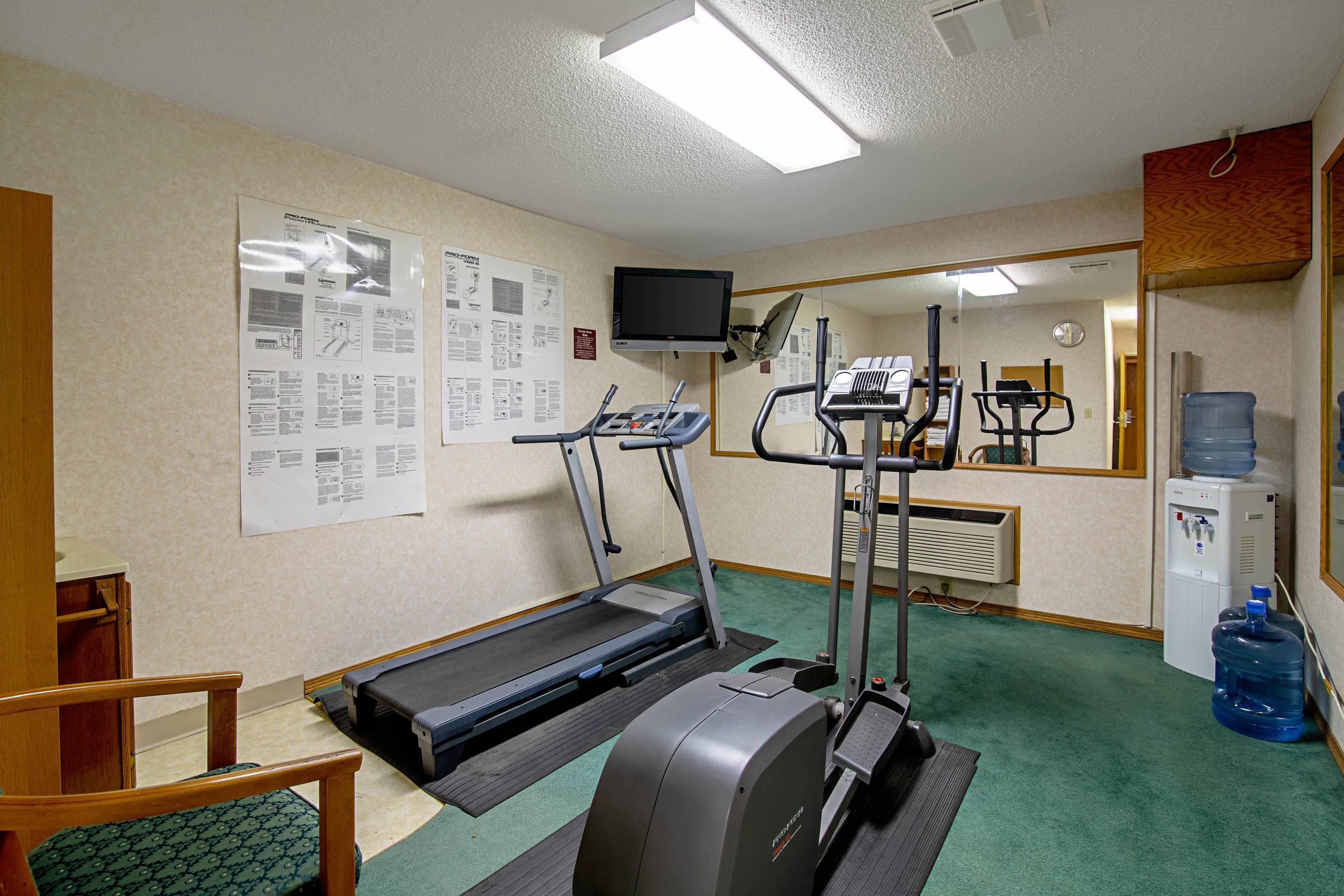 A fitness room with treadmills, an elliptical, a water cooler, and exercise equipment.