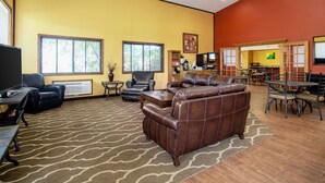 A spacious living room with a brown leather sofa, a coffee table, and a dining area with a table and chairs. - Quality Inn Aberdeen (Aberdeen)