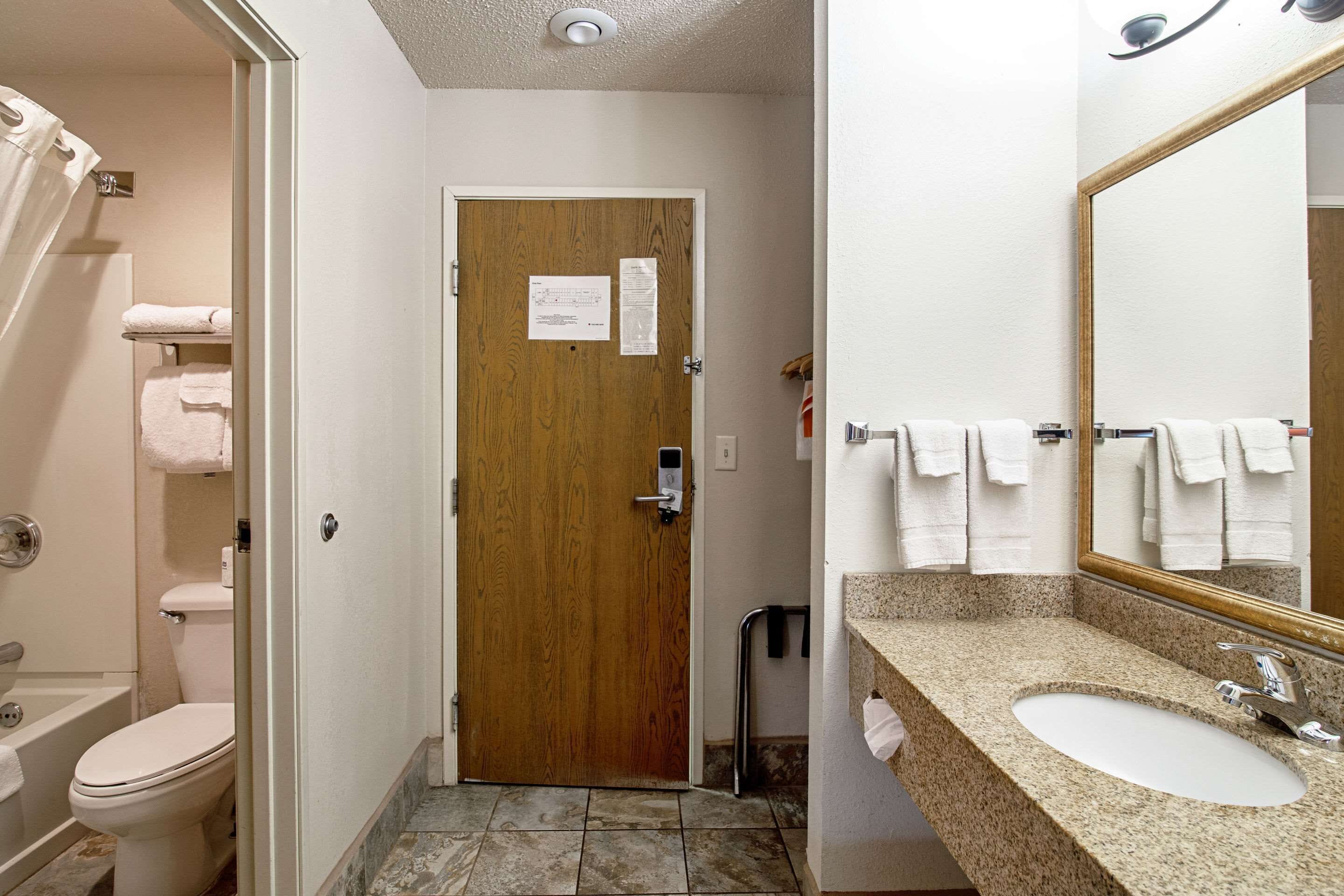 A bathroom with a wooden door, a white sink, and a mirror.