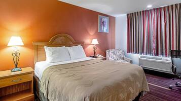 A hotel room with a bed, bedside lamps, a telephone, a chair, an air conditioning unit, and a window with curtains.