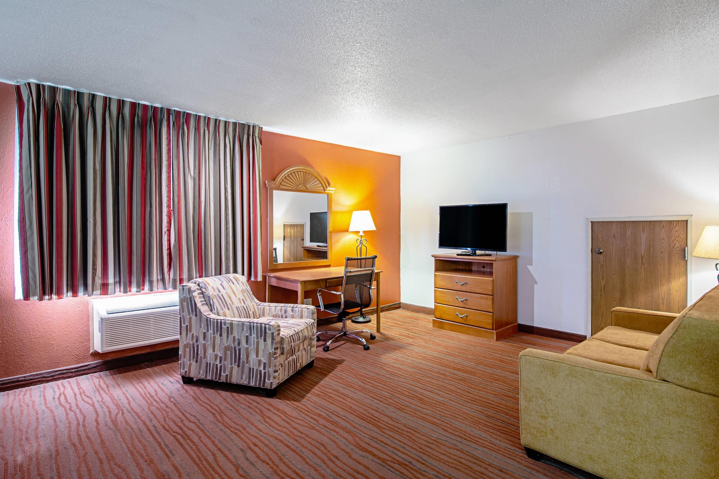 Ein Hotelzimmer mit einem Bett, einem Schreibtisch mit Stuhl, einem Fernseher und einem Kleiderschrank.