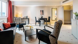 Une chambre d’hôtel moderne dotée d’un espace salon, d’une table à manger et offrant une vue sur la ville.