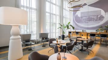 A modern hotel lobby with a large white lamp, comfortable seating, a large window, and a projection screen.