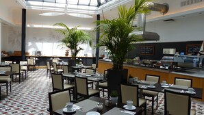 Un restaurant spacieux avec de hauts plafonds, de grandes fenêtres et différents types d’aménagements pour s’asseoir.