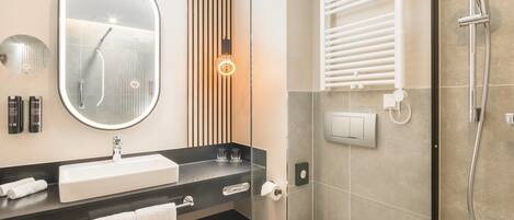 A modern bathroom with a large mirror, a sink, a toilet, and a shower with a handheld showerhead.