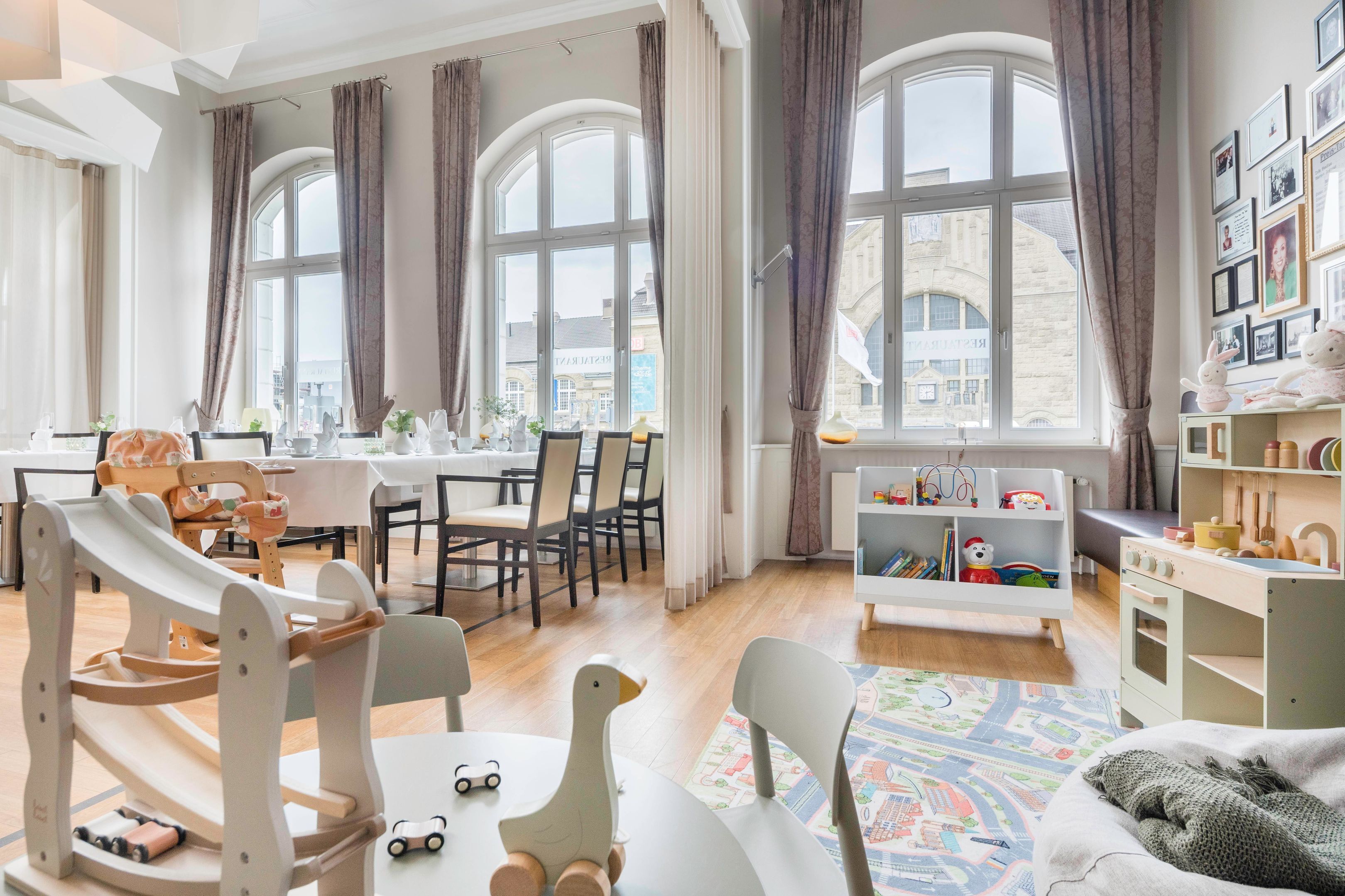 Een ruime kamer met grote ramen, een eethoek en een kinderspeelruimte.