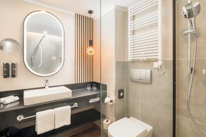 Een moderne badkamer met een grote spiegel, een wastafel, een toilet en een douche met een handdouche.