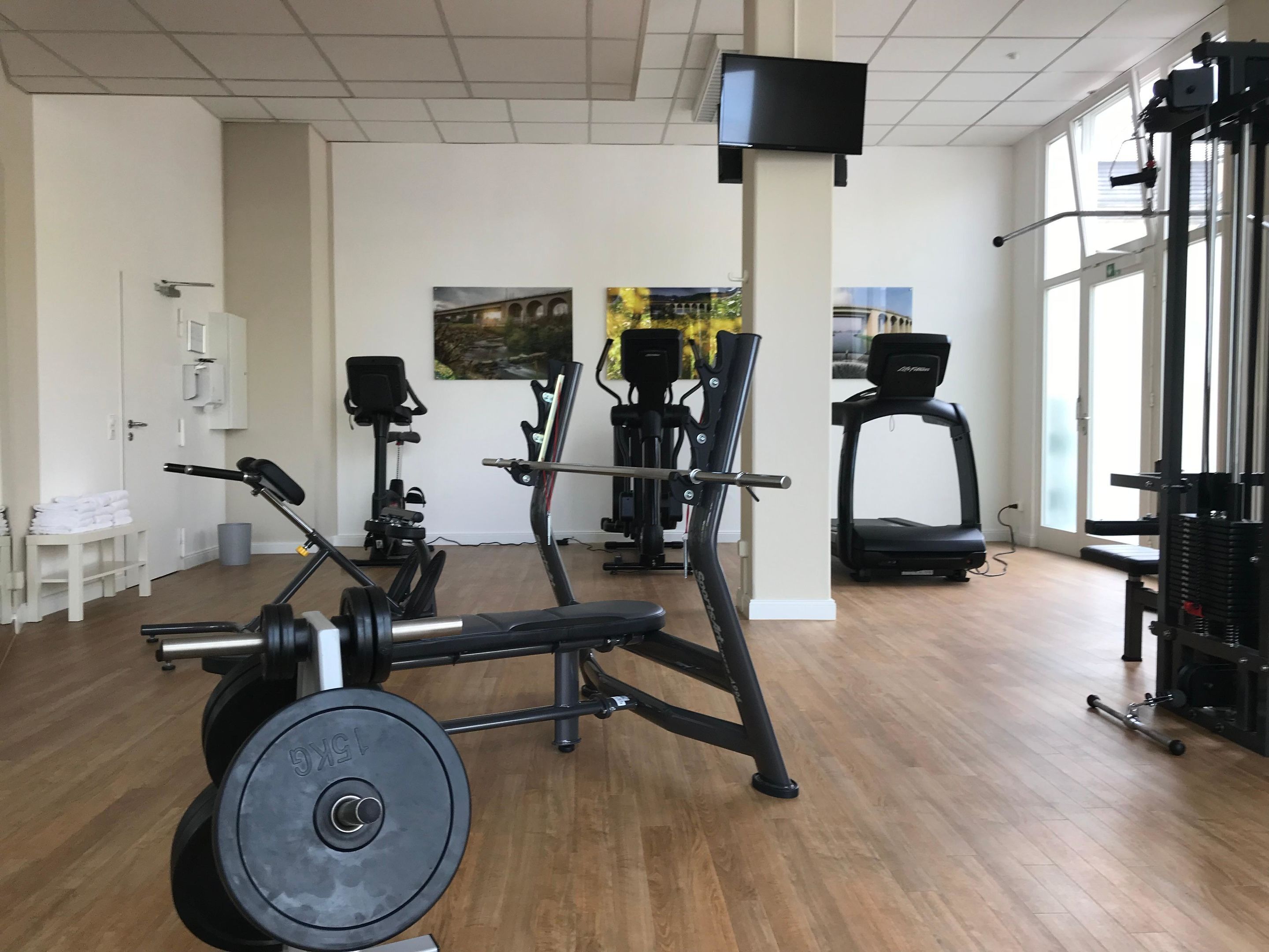 A gym with exercise equipment, a TV, and large windows.