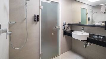 A modern bathroom with a glass-enclosed shower, a sink with a black countertop, and a mirror above the sink.