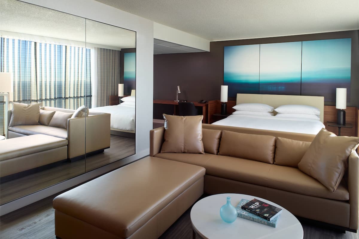 Een moderne hotelkamer met een groot bed, een bank, een salontafel en een bureau.