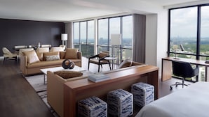 Una habitación de hotel moderna con una cama grande, un escritorio de madera, un sofá y una zona de comedor.