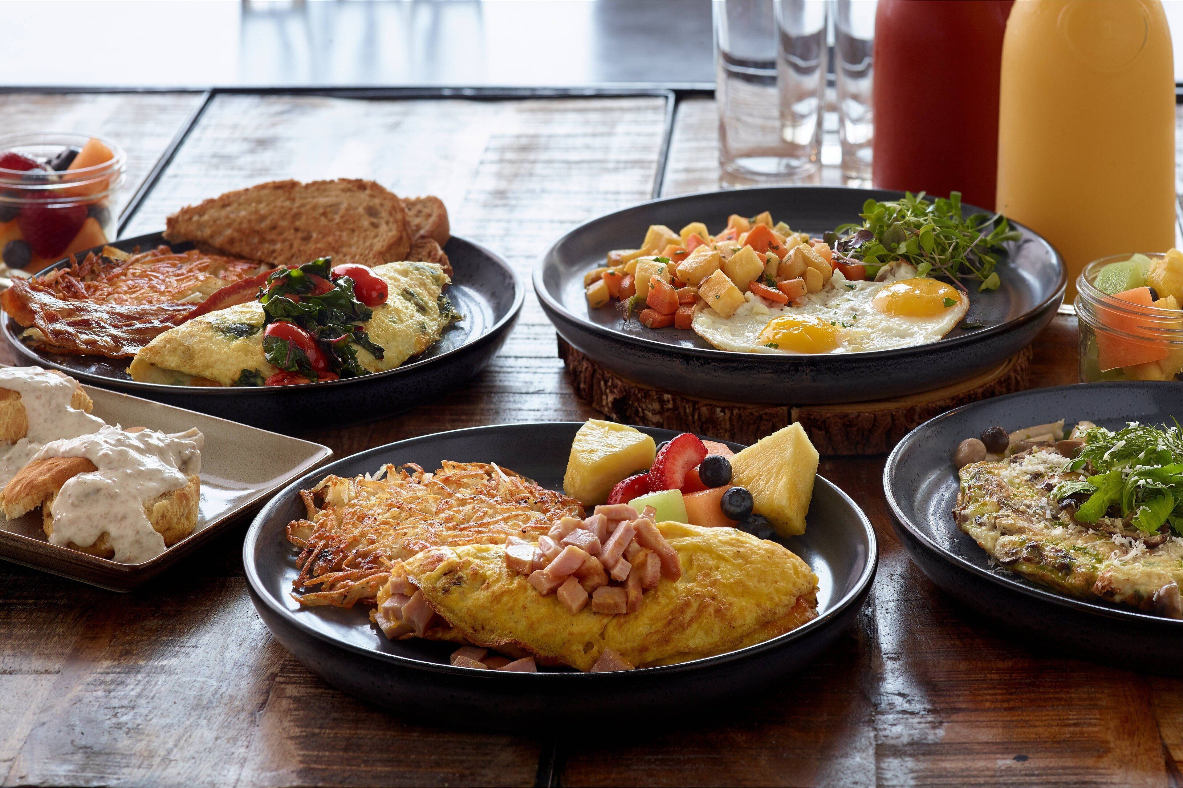 Un assortiment de plats pour le petit-déjeuner comprenant divers éléments, notamment des œufs, des toasts et des fruits.