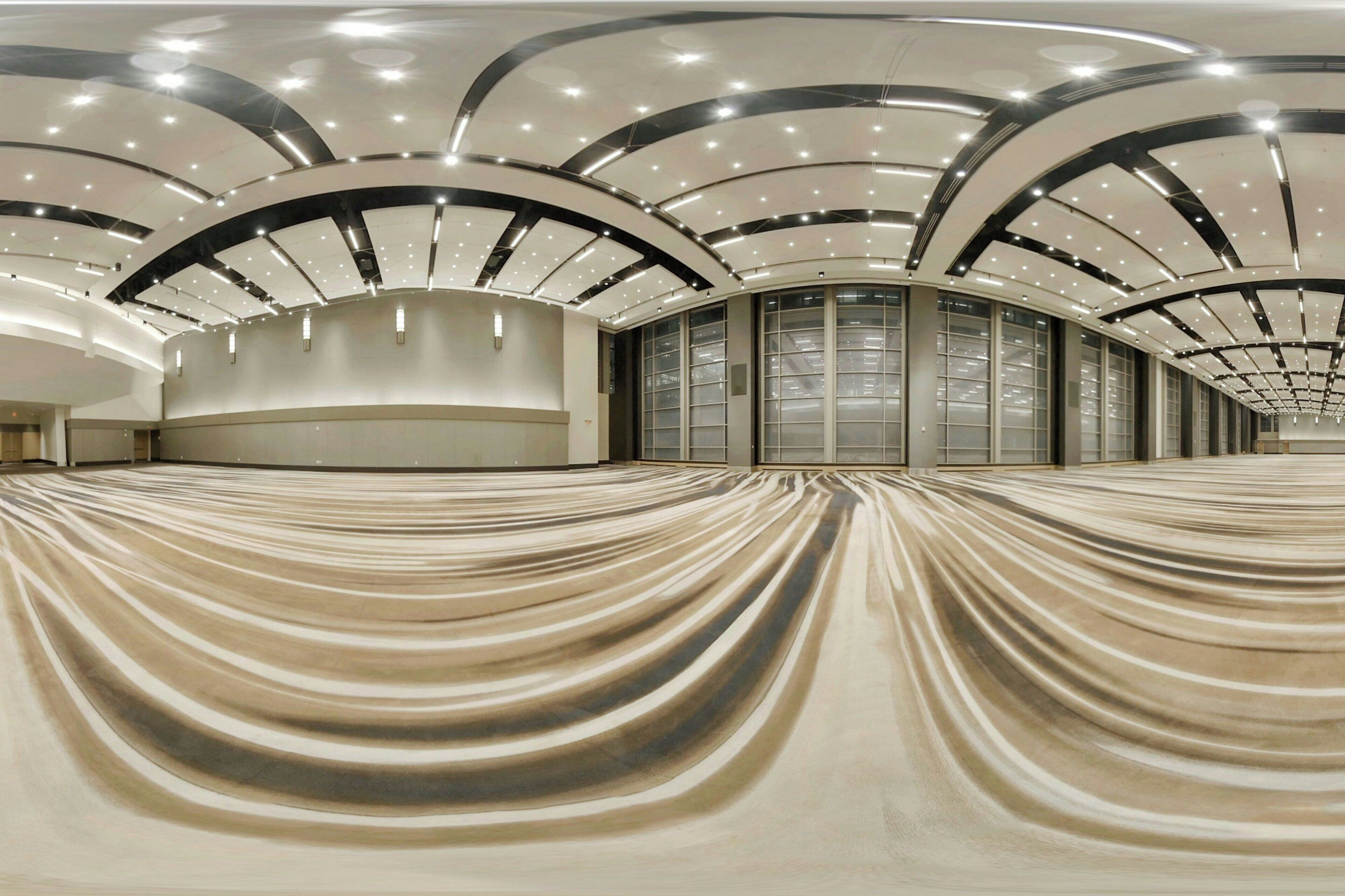 A spacious, modern hotel interior with a curved ceiling and a central seating area.