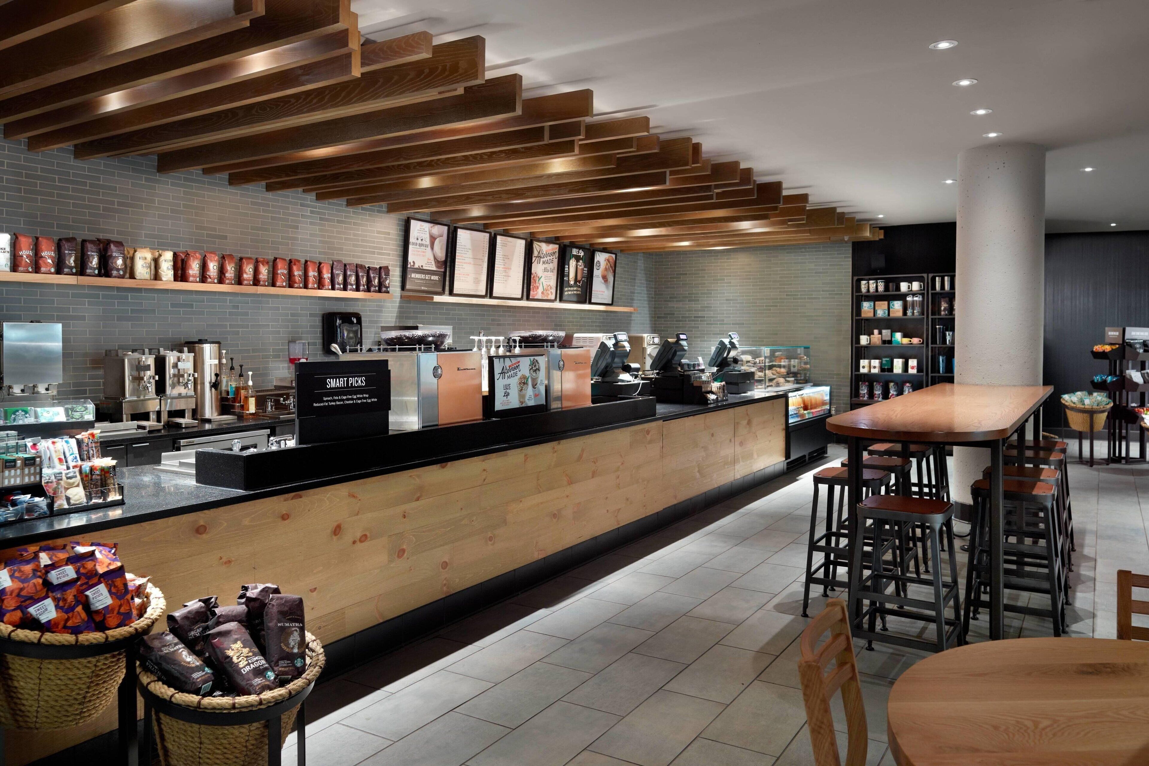 A modern coffee shop interior with a wooden counter, coffee machines, and seating area.