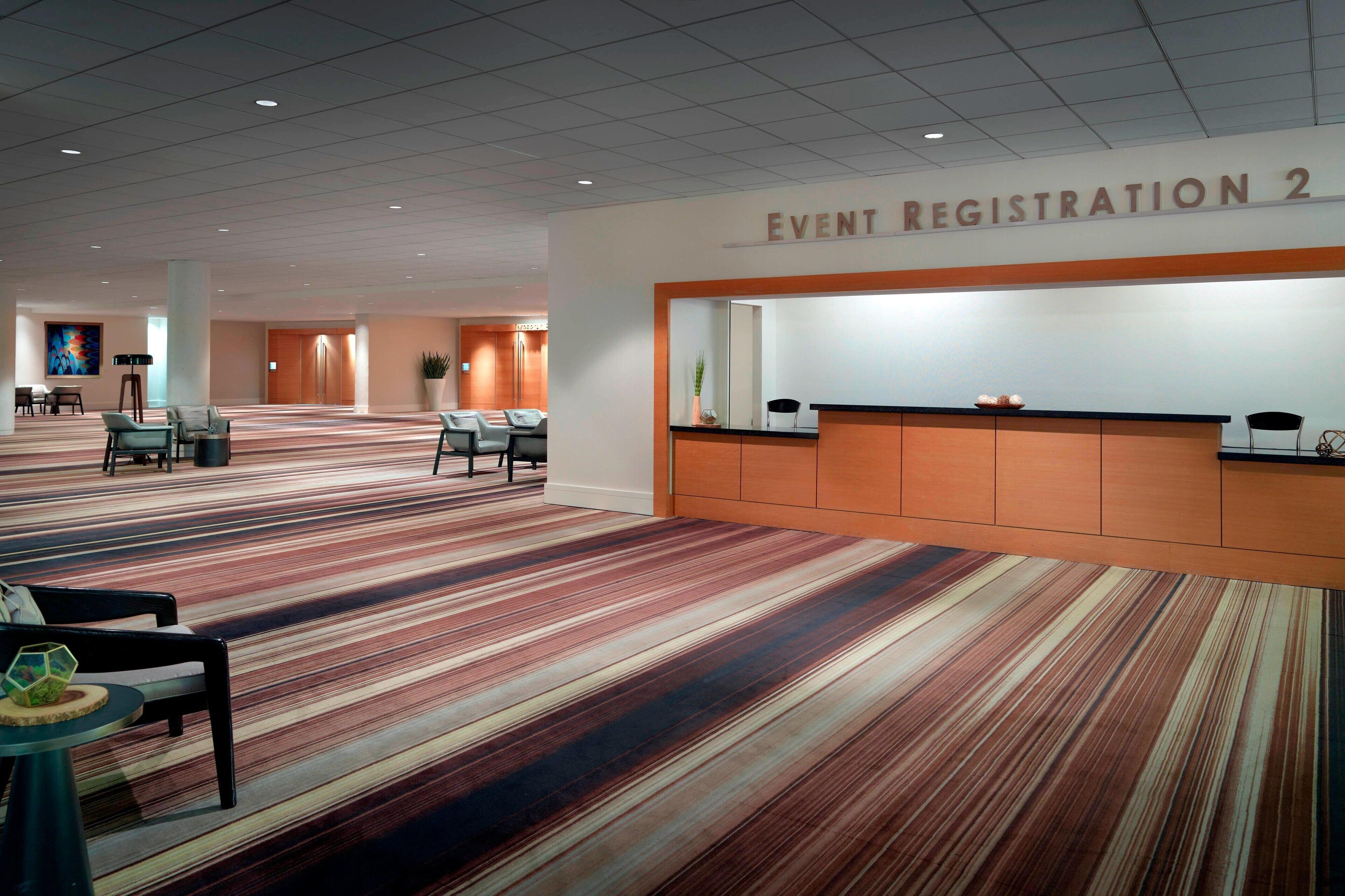 A spacious event registration area with a carpeted floor and a reception desk.