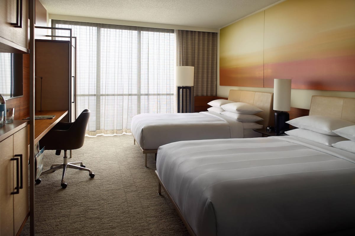 Een hotelkamer met twee bedden, een bureau en een stoel.