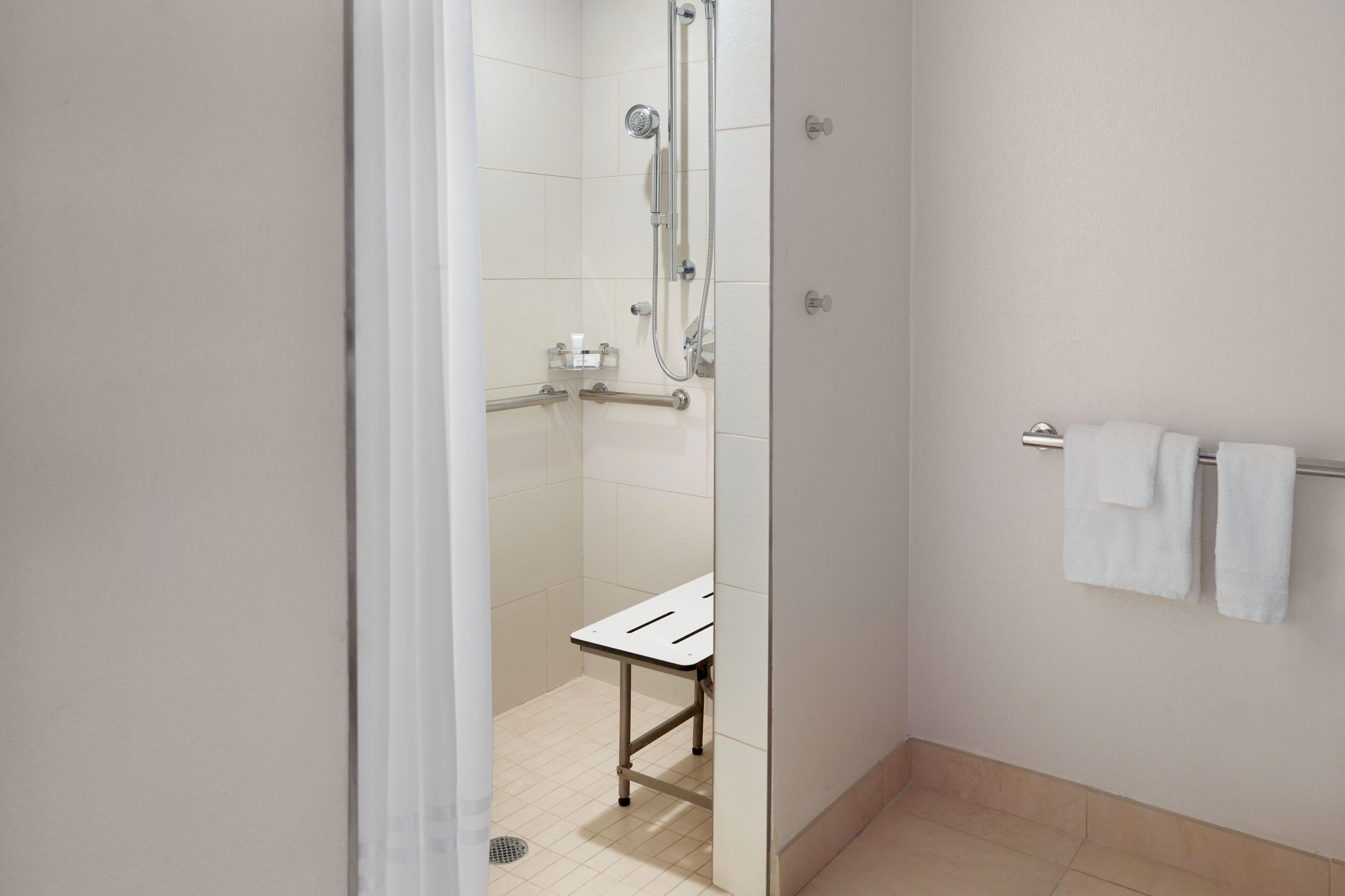 A modern bathroom with a shower, a toilet, and a towel rack.