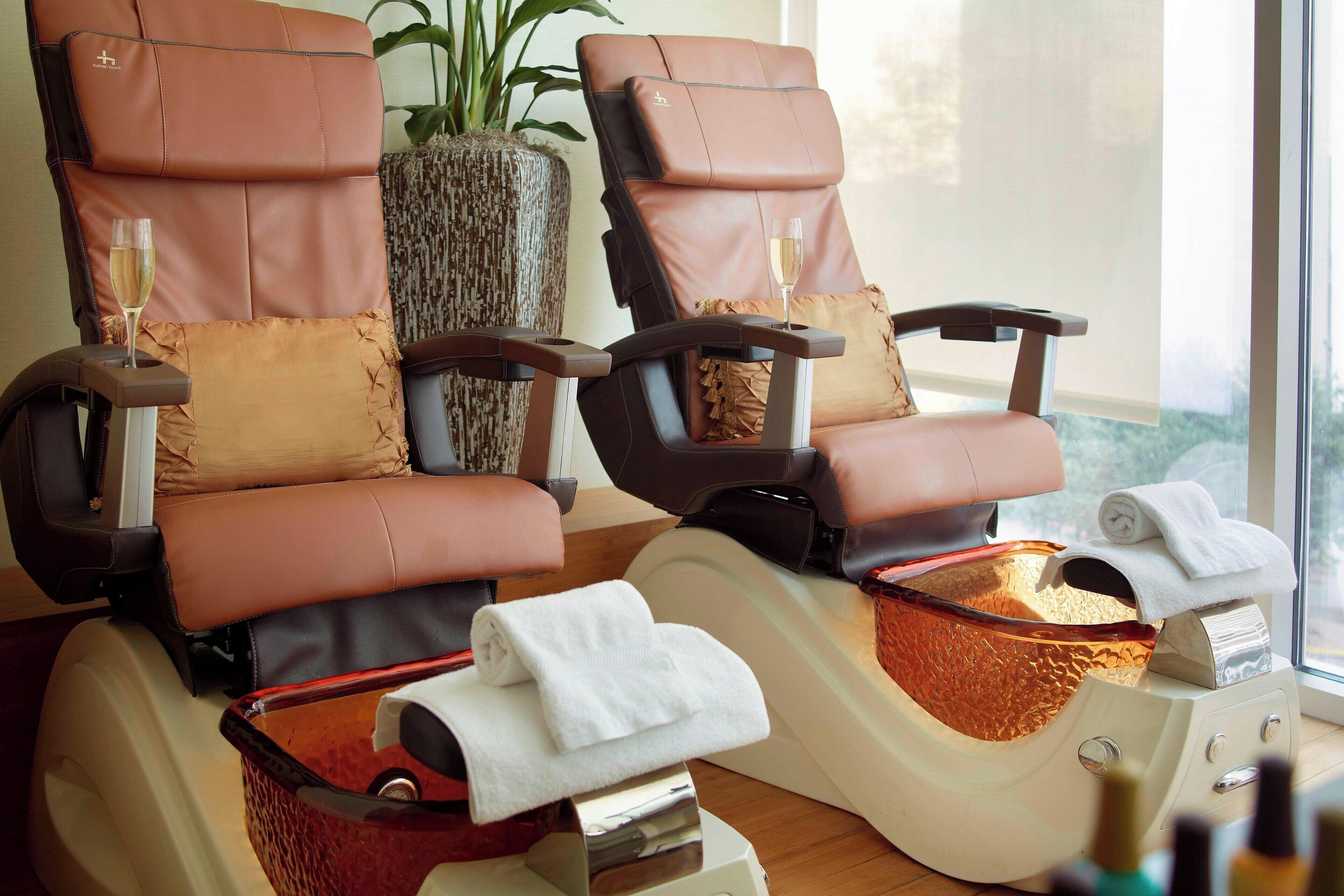 Two massage chairs with towels and a glass of wine.