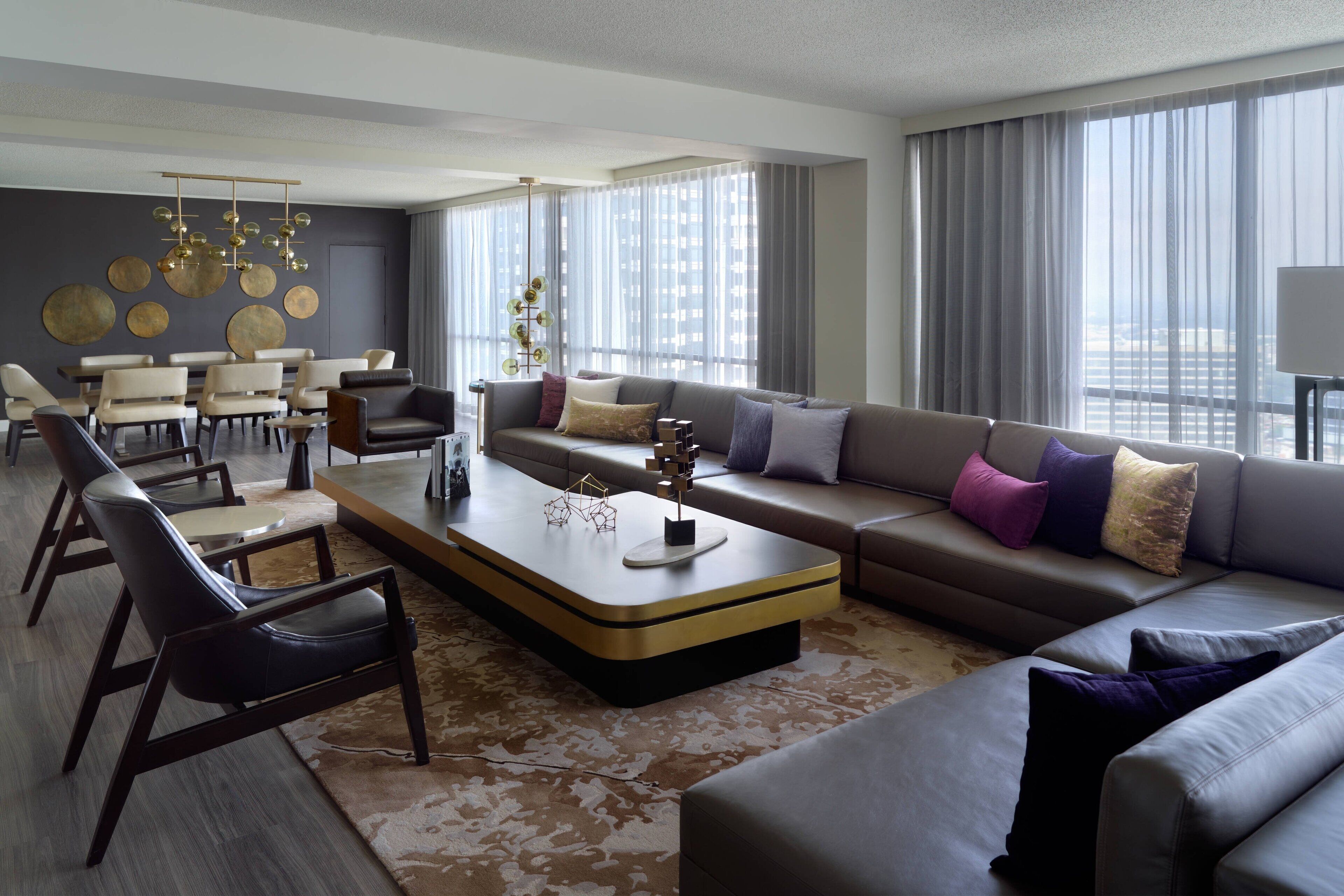 A modern living room with a sectional sofa, a coffee table, and a dining area with chairs and a table.