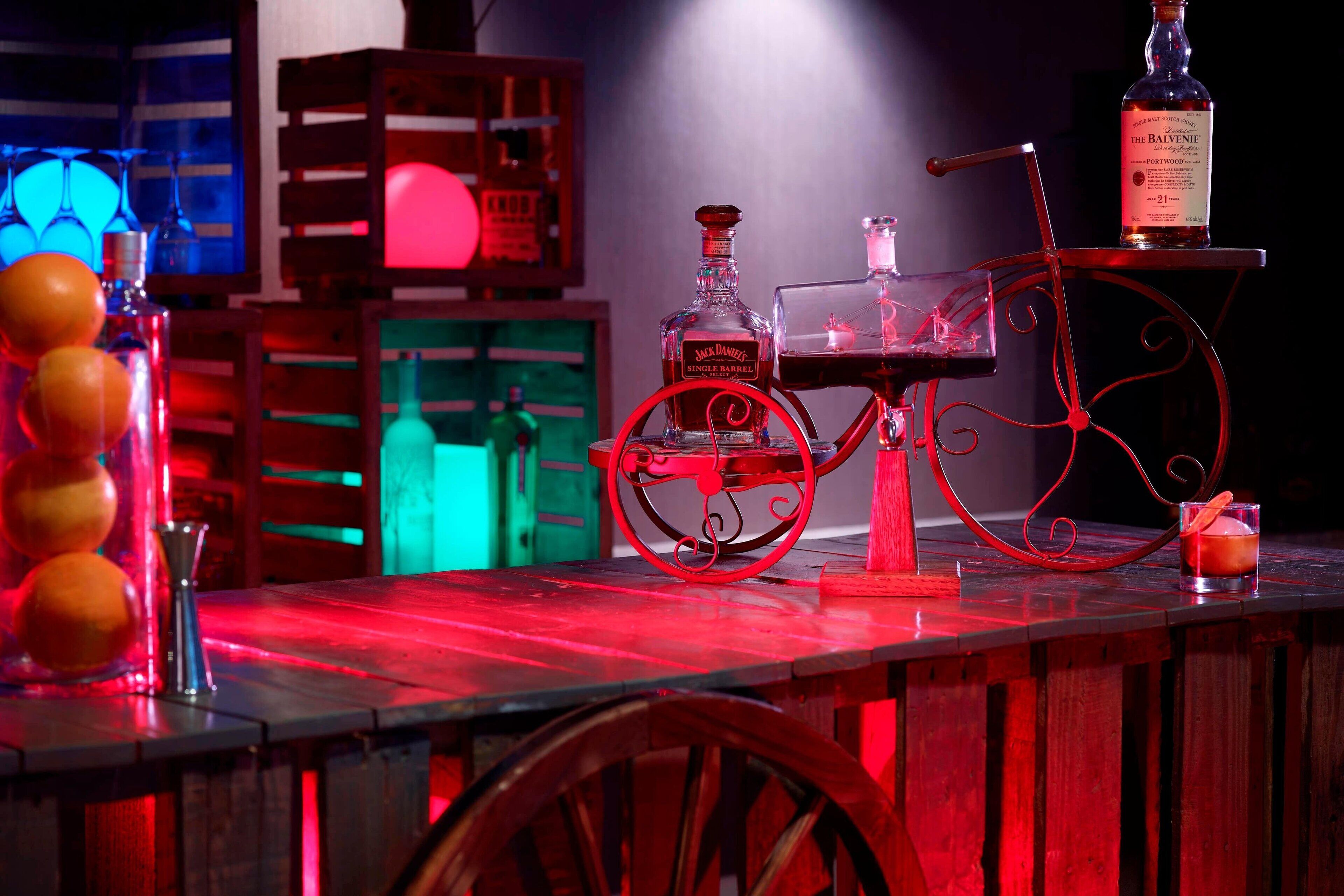 Una zona de bar con un carrito antiguo, una botella de Jack Daniel's y una copa de whisky.