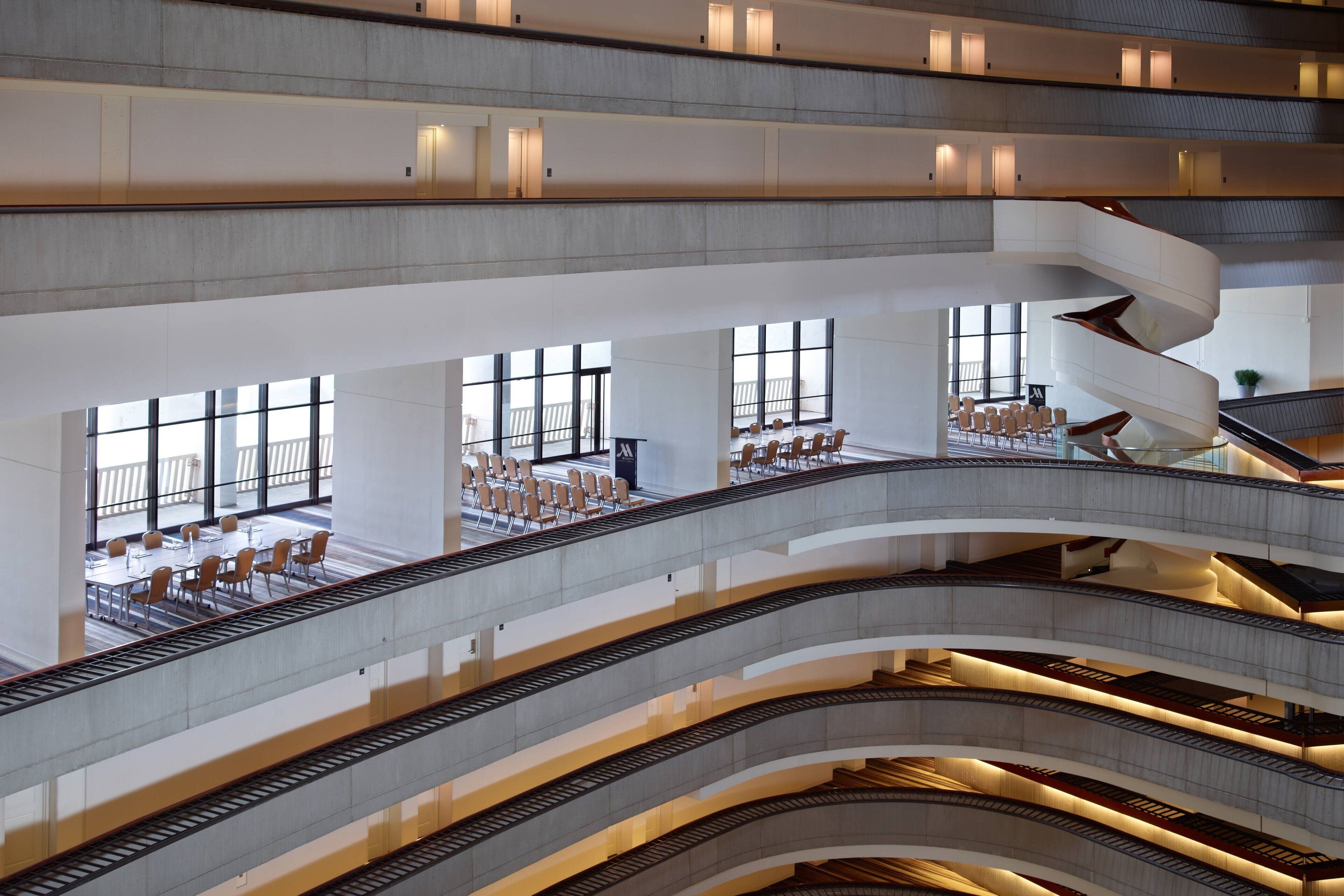 Ein mehrgeschossiges Atrium mit einer zentralen Wendeltreppe, großen Fenstern und Sitzbereichen.