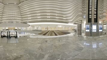 A spacious lobby with a curved ceiling, escalators, and a central open area.