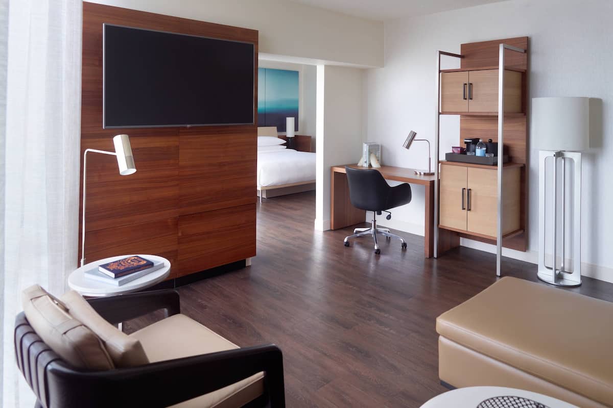 Een hotelkamer met een bed, een bureau, een stoel, een televisie, een lamp en een kast.