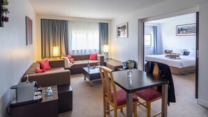 Une chambre d’hôtel moderne comprenant un espace de vie, une table à manger et une chambre à coucher séparée.
