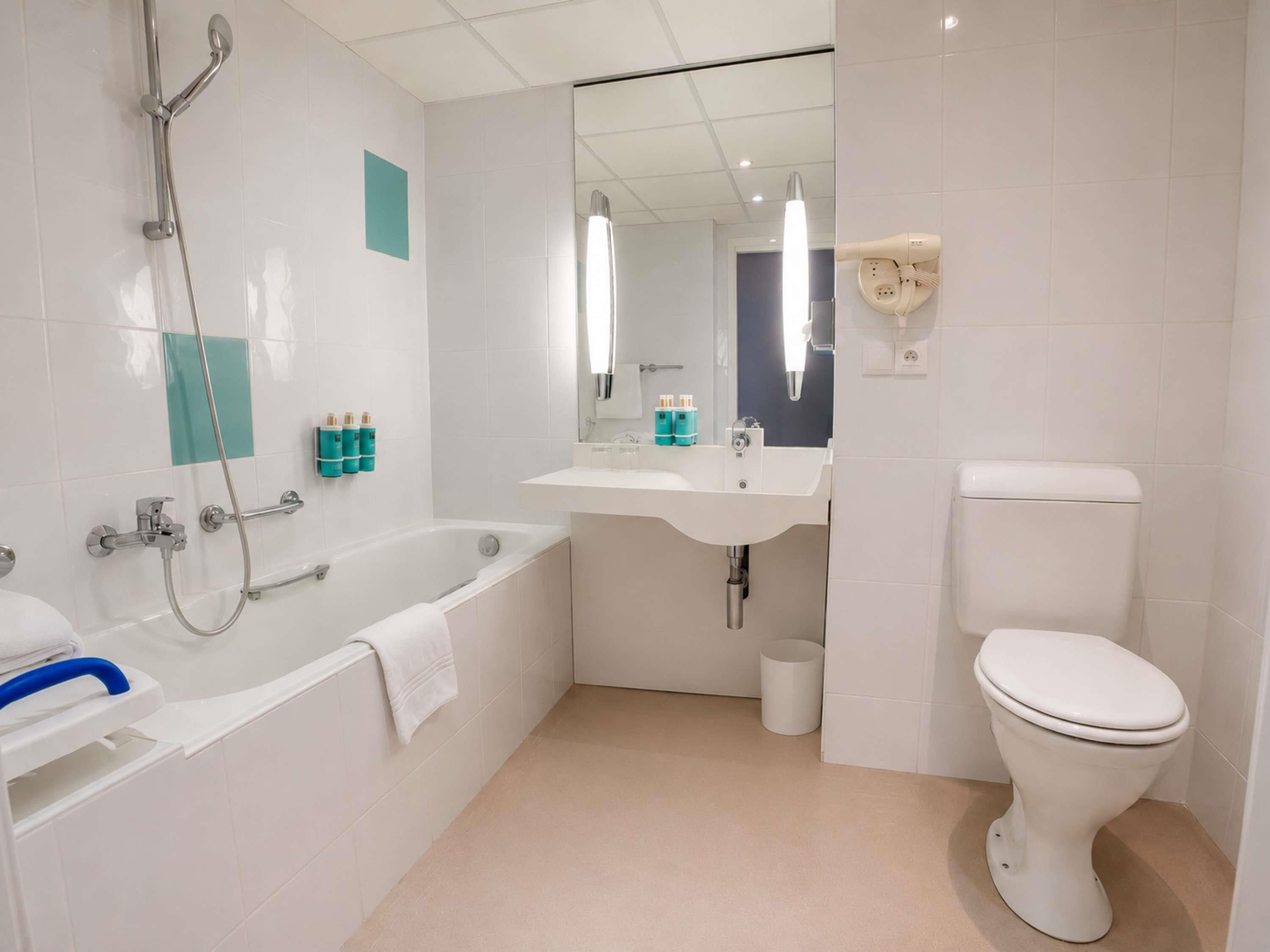 Un baño moderno con bañera, lavabo, inodoro y espejo.