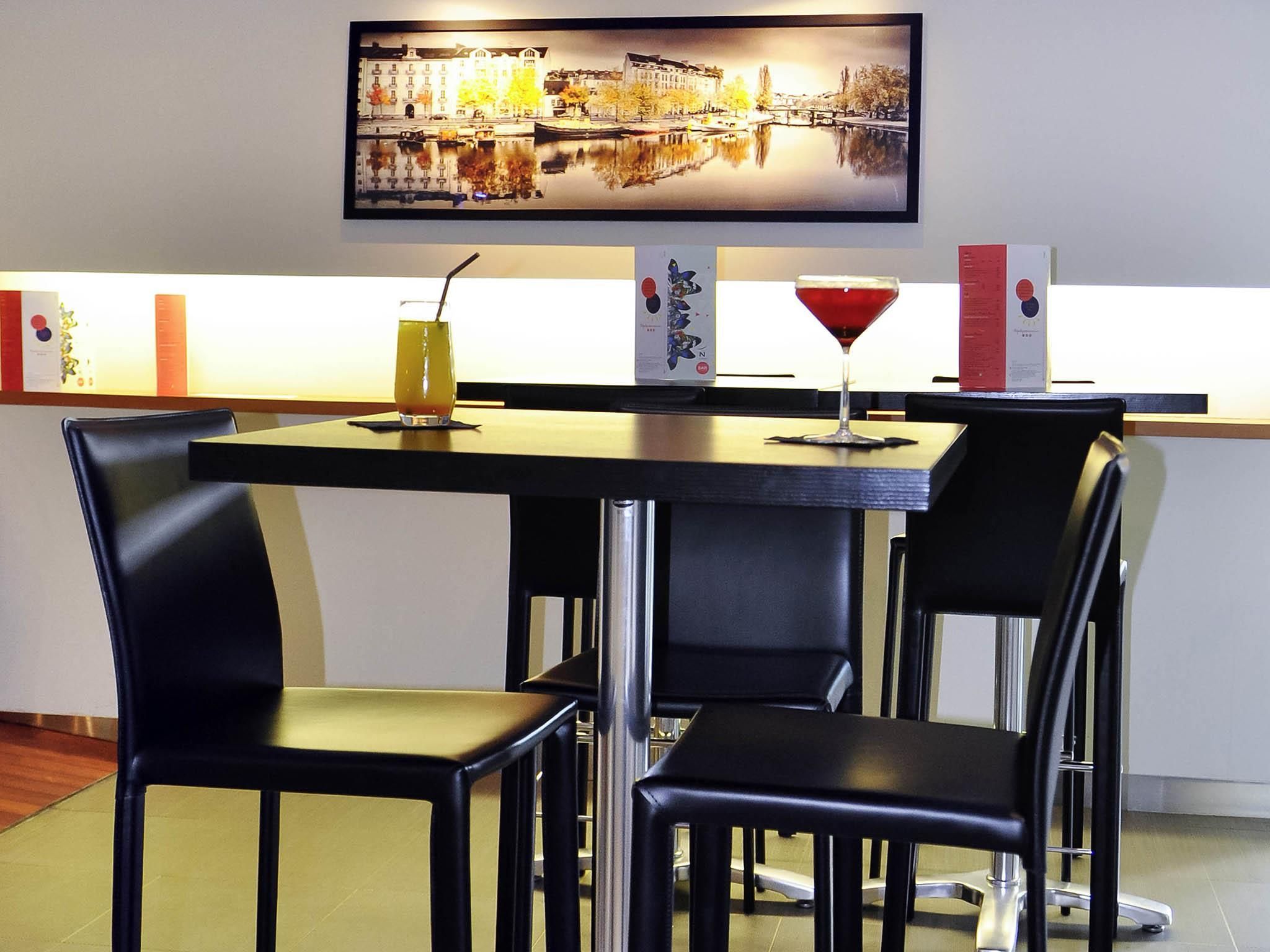 Un área de bar con una mesa, sillas, un cuadro enmarcado y una copa de martini.