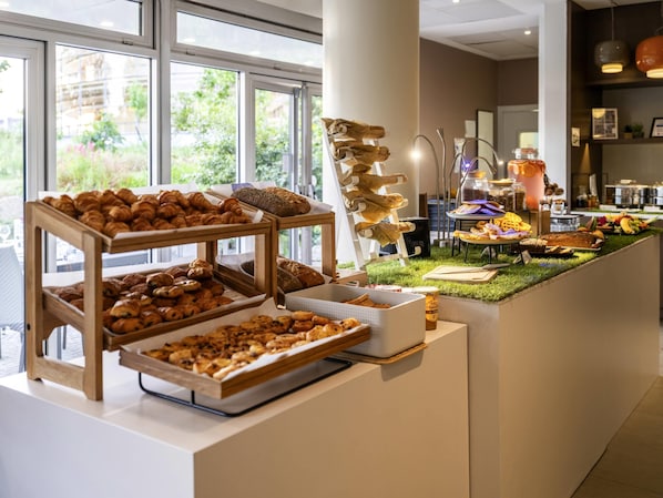 A breakfast buffet with various pastries and a coffee station.