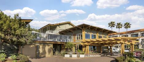 A hotel with a covered outdoor area, a gated entrance, and a landscaped driveway.